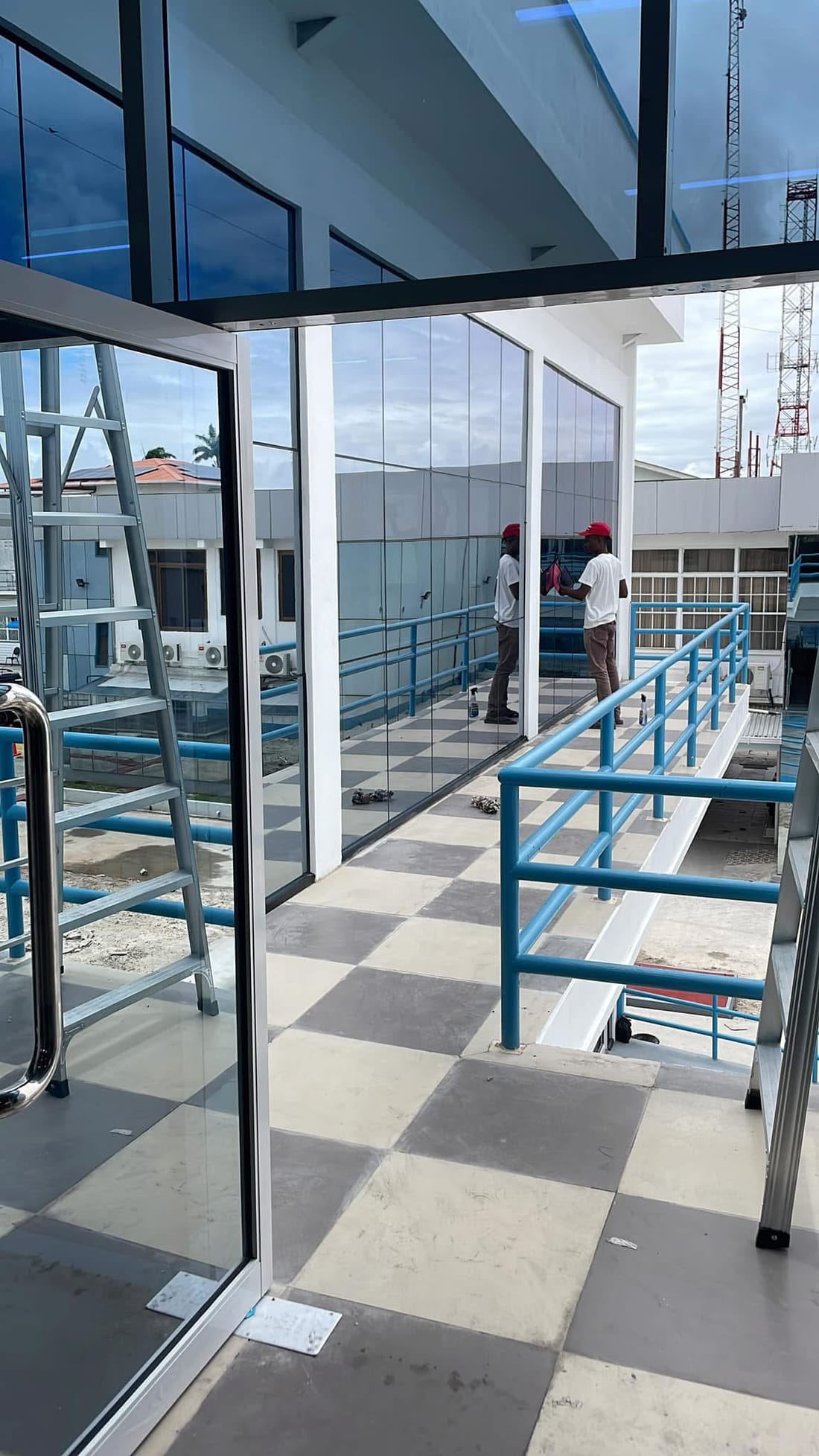 A CDCS worker cleaning the full-height glass facade of a commercial building in Guyana